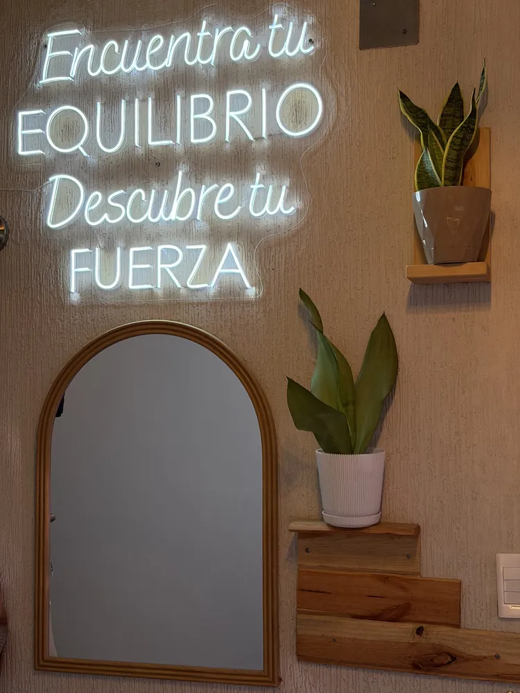 Espejo de arco con plantas y repisas de madera junto al neón del salón