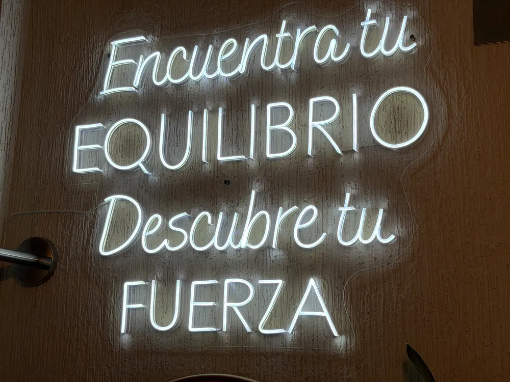 Neón con la frase Encuentra tu equilibrio, descubre tu fuerza en la entrada